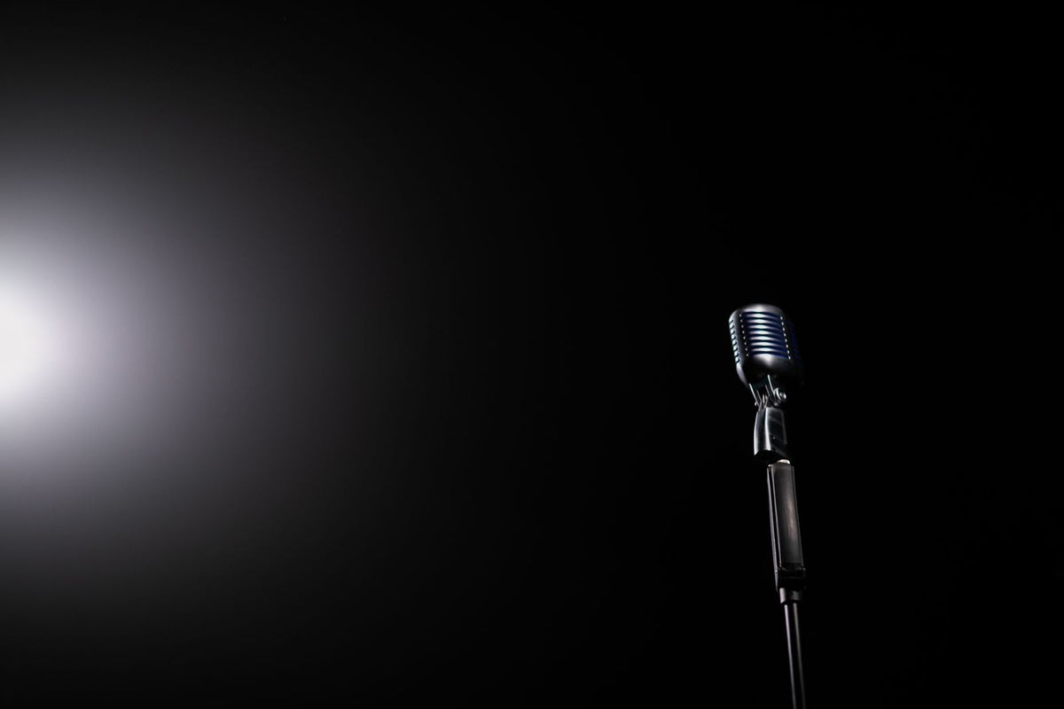 Vintage silver microphone illuminated by a single spotlight against a dark stage — evoking the Cantopop era of Anita Mui