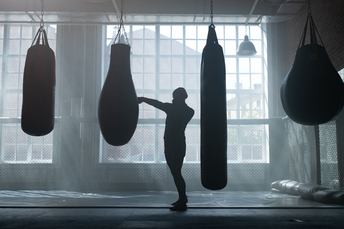 Silhouette of a fighter shadow-boxing in a gym at golden hour — era imagery for a Bruce Lee tribute