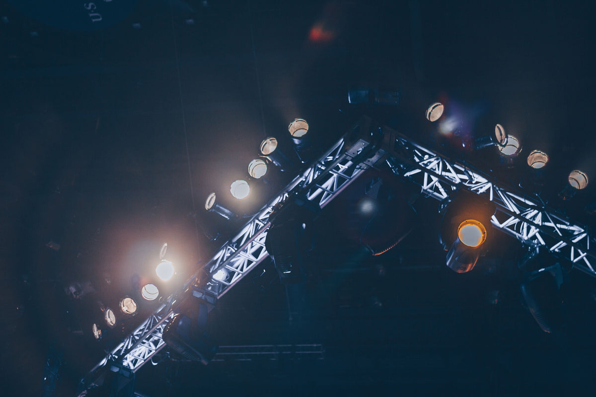 Bright concert stage lights illuminating a packed music venue