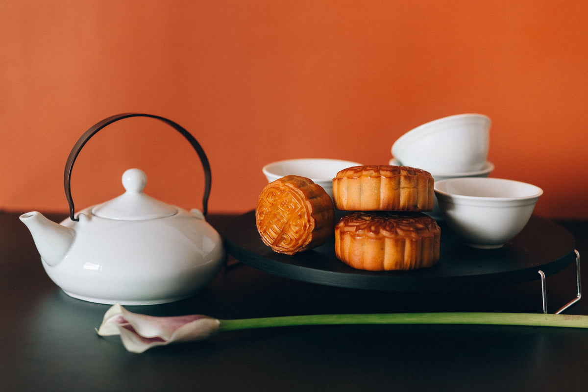 Traditional Chinese mooncakes arranged with a white teapot and teacups ready for Mid-Autumn Festival
